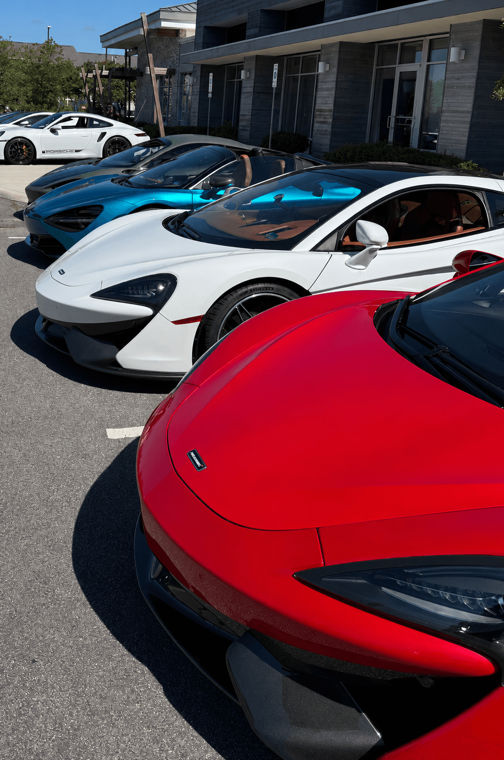 A tightly framed lineup of McLarens and a Porsche at a Cars & Coffee gathering